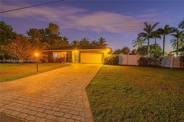 view of front facade with a garage, fence, decorative driveway, and a front yard