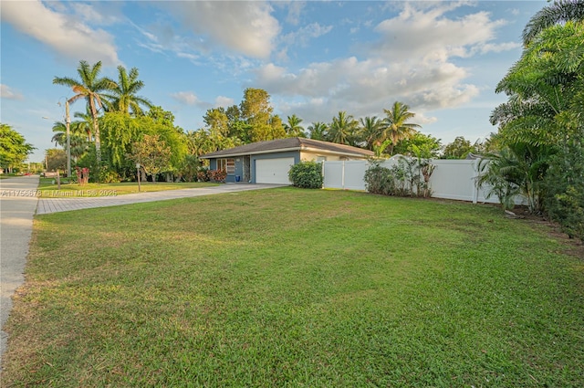 view of yard featuring a garage, driveway, and fence