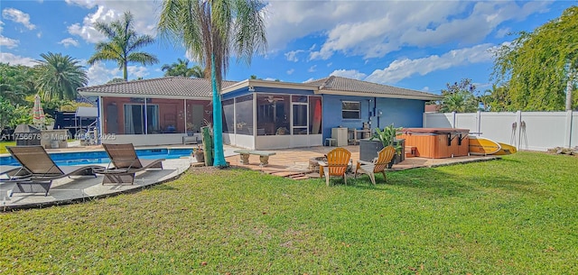 back of house featuring a lawn, a hot tub, a sunroom, a patio area, and a fenced backyard