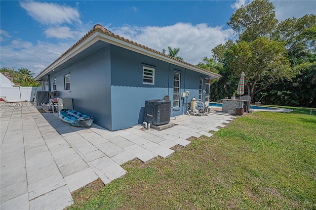 view of side of home with fence, a yard, a fenced in pool, stucco siding, and a patio area