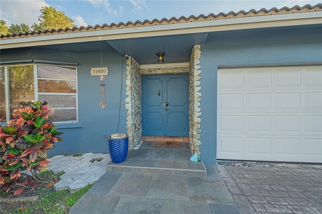 property entrance featuring an attached garage and stucco siding