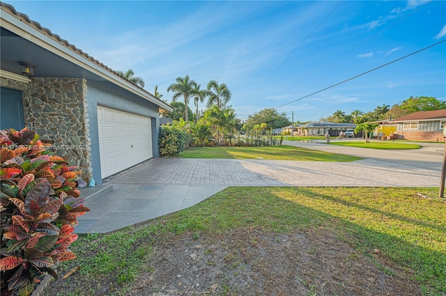 view of yard with a garage and decorative driveway