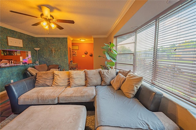 living room featuring wallpapered walls, a textured ceiling, a ceiling fan, and crown molding