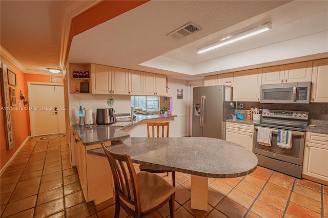 kitchen with a raised ceiling, visible vents, appliances with stainless steel finishes, a textured ceiling, and a peninsula