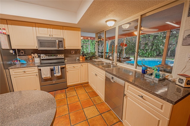 kitchen featuring a textured ceiling, ceiling fan, light tile patterned flooring, a sink, and appliances with stainless steel finishes