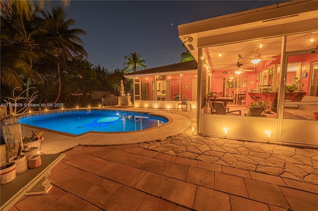 pool at night with a patio area and an outdoor pool