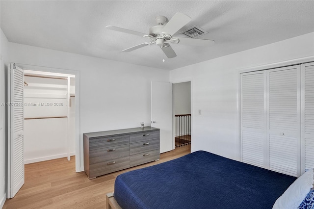 bedroom featuring a closet, visible vents, light wood-style flooring, a ceiling fan, and a textured ceiling