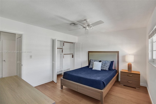 bedroom with visible vents, light wood-style flooring, ceiling fan, a textured ceiling, and baseboards