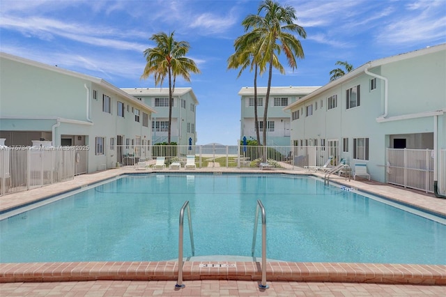 pool with a residential view, fence, and a patio