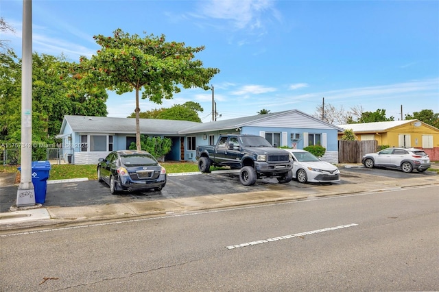 view of front of house with uncovered parking and fence