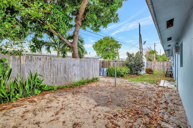 view of yard with an AC wall unit and a fenced backyard