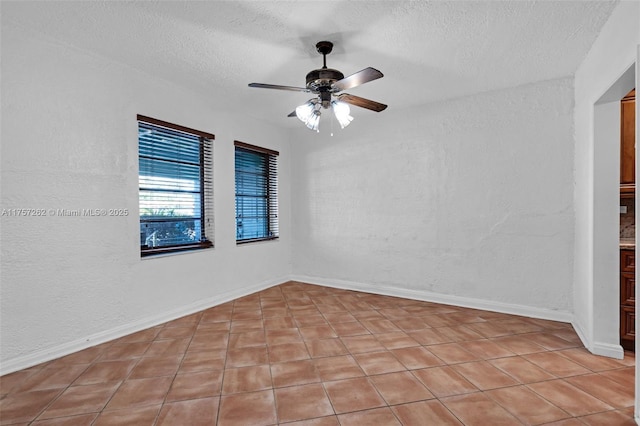 empty room with a textured wall, ceiling fan, a textured ceiling, and baseboards