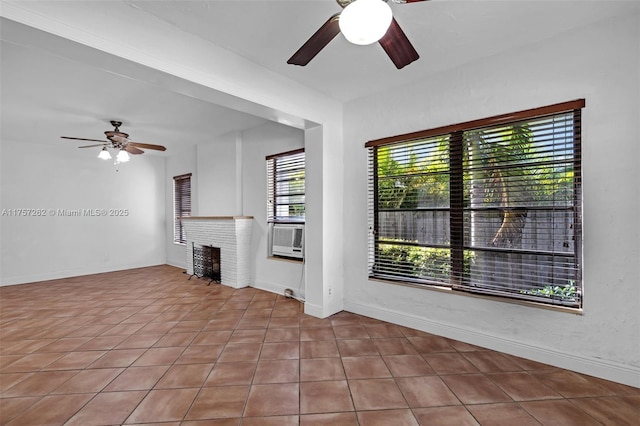 unfurnished living room featuring a brick fireplace, ceiling fan, baseboards, and cooling unit