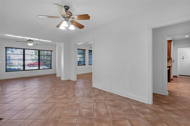 empty room with light tile patterned floors, baseboards, baseboard heating, and a ceiling fan