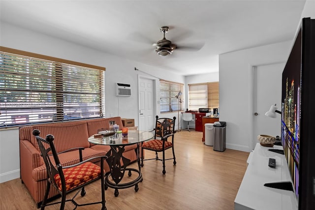 dining area featuring ceiling fan, an AC wall unit, baseboards, and light wood-style floors