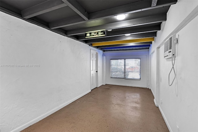 empty room featuring concrete flooring, a wall unit AC, and baseboards