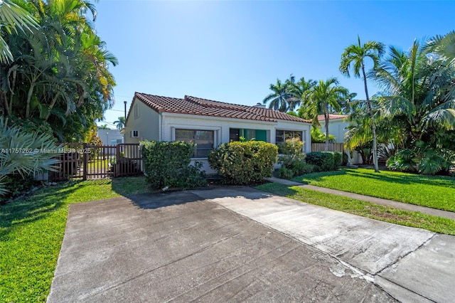 view of front of home featuring a tile roof, a gate, fence, and a front yard