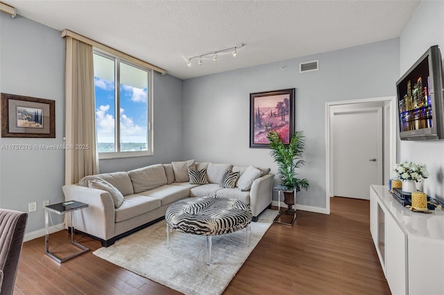 living area featuring baseboards, a textured ceiling, visible vents, and wood finished floors