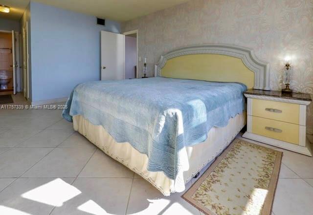 bedroom with light tile patterned flooring, visible vents, and wallpapered walls