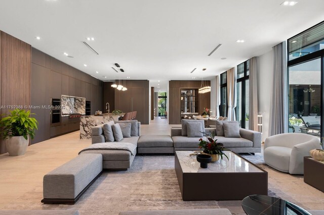 living room featuring light wood finished floors, expansive windows, a notable chandelier, and recessed lighting