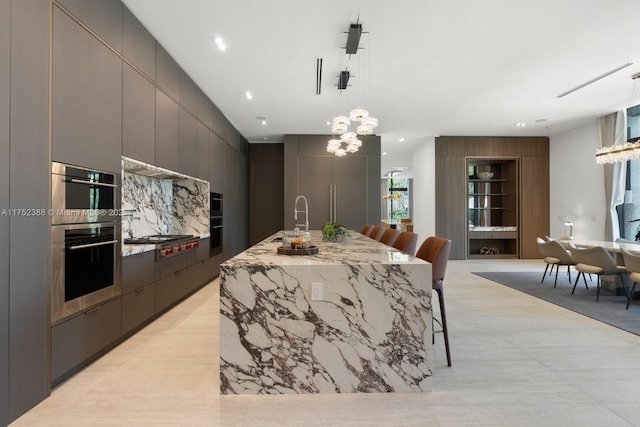 kitchen featuring appliances with stainless steel finishes, an island with sink, modern cabinets, and a sink