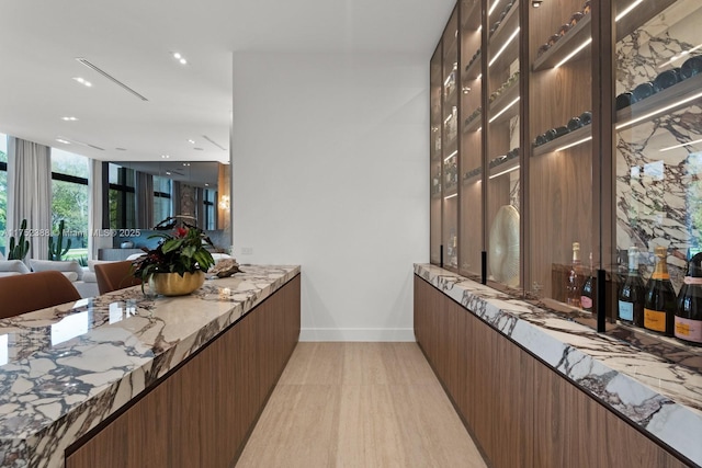 bar with floor to ceiling windows, light wood finished floors, and baseboards