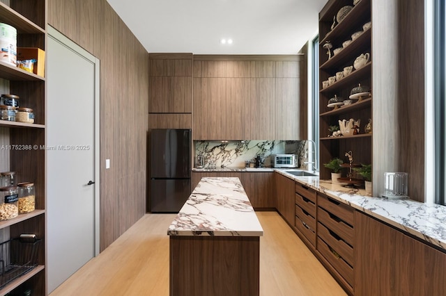 kitchen featuring a sink, a kitchen island, freestanding refrigerator, open shelves, and modern cabinets