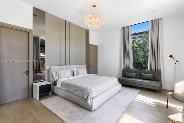 bedroom featuring expansive windows, visible vents, light wood-style flooring, and a notable chandelier