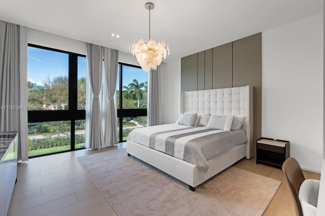 bedroom featuring light wood-style floors, access to exterior, and an inviting chandelier