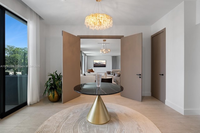 hall with a notable chandelier, light wood-style flooring, and baseboards