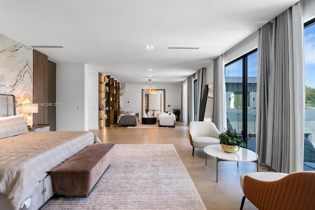 bedroom with access to outside, an accent wall, and wood finished floors