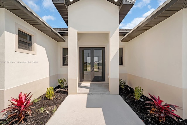 view of exterior entry with french doors and stucco siding