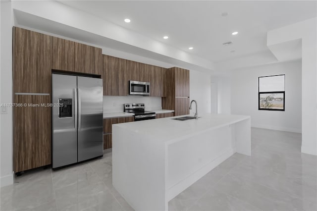 kitchen with a raised ceiling, light countertops, appliances with stainless steel finishes, a sink, and modern cabinets