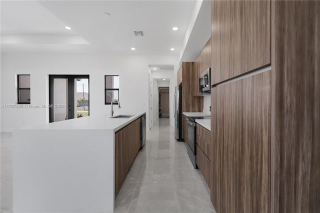 kitchen featuring modern cabinets, stainless steel appliances, a sink, and light countertops