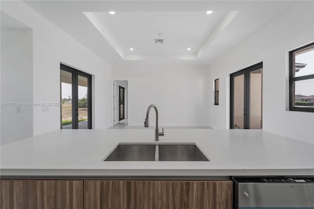 kitchen featuring a sink, visible vents, french doors, dishwasher, and a tray ceiling