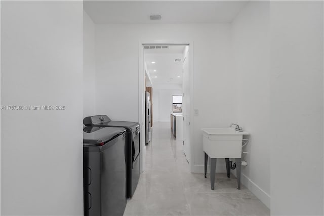 laundry area with laundry area, washing machine and dryer, visible vents, and baseboards