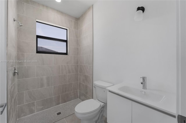 full bathroom featuring vanity, a tile shower, and toilet