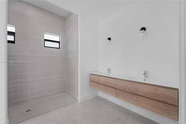 full bath featuring tile patterned flooring, a tile shower, and baseboards