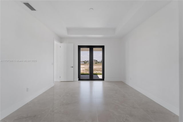 spare room featuring french doors, a raised ceiling, visible vents, and baseboards