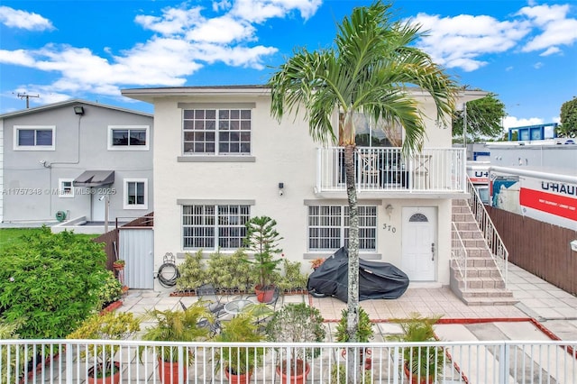 view of front of home with a patio, fence, stairway, and stucco siding