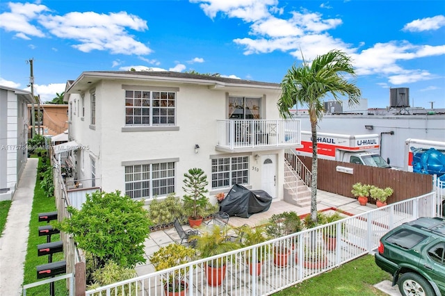 view of front of property with a patio, fence, and stucco siding