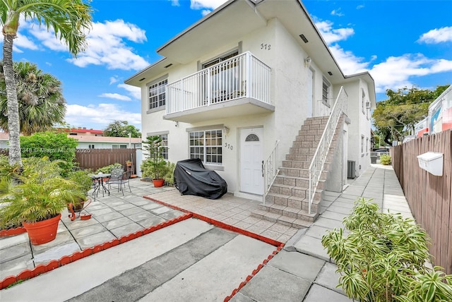 back of house with stairs, fence private yard, a patio, and stucco siding