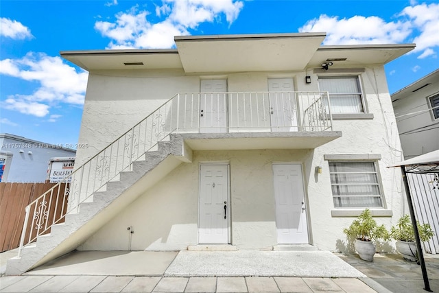 exterior space with a balcony, stairs, fence, and stucco siding