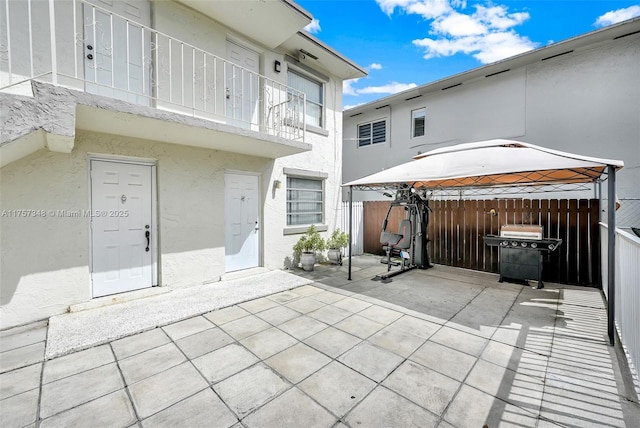 rear view of house featuring a patio area, fence, and stucco siding