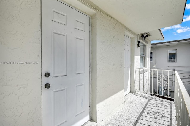 view of exterior entry with a balcony and stucco siding