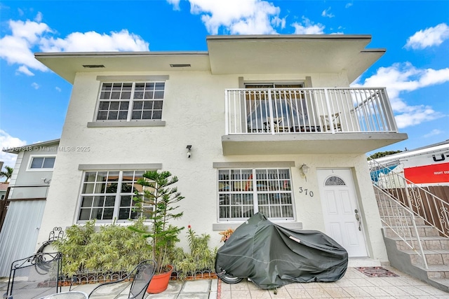 back of property with a balcony and stucco siding