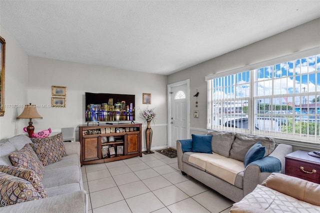 living area featuring a textured ceiling, light tile patterned floors, and baseboards