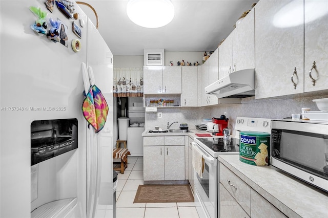 kitchen featuring tasteful backsplash, light countertops, a sink, white appliances, and under cabinet range hood