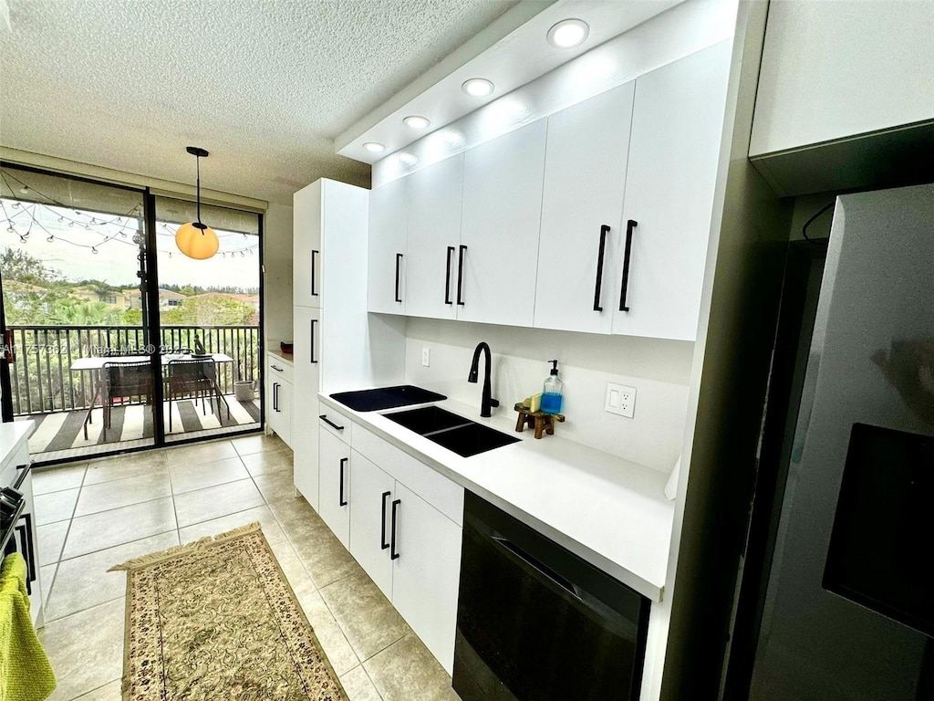 kitchen featuring light countertops, hanging light fixtures, freestanding refrigerator, a sink, and dishwasher