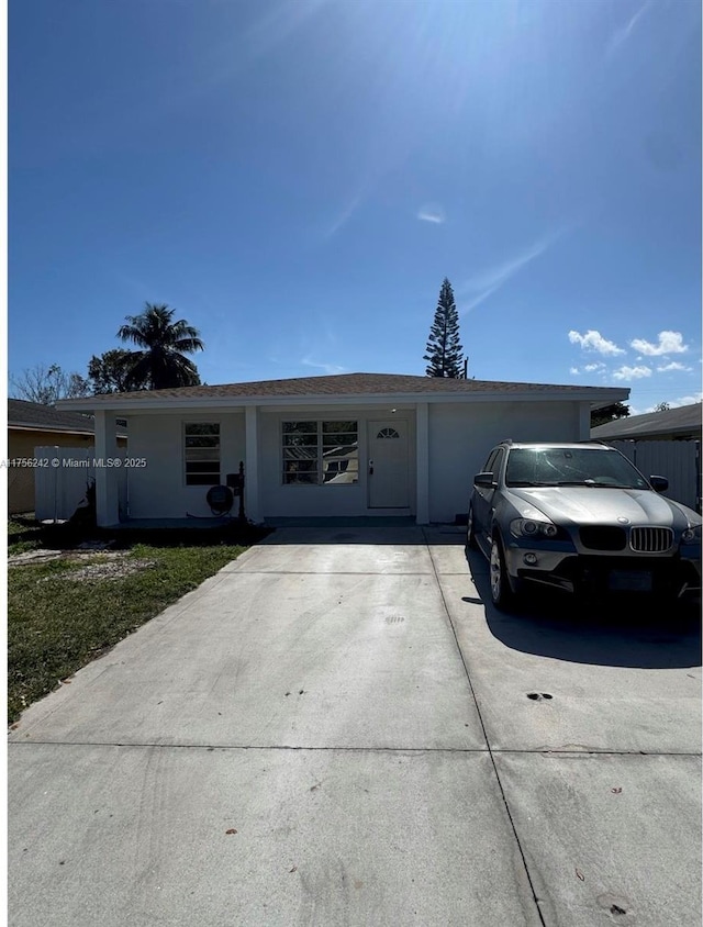 ranch-style house with driveway, an attached garage, and stucco siding